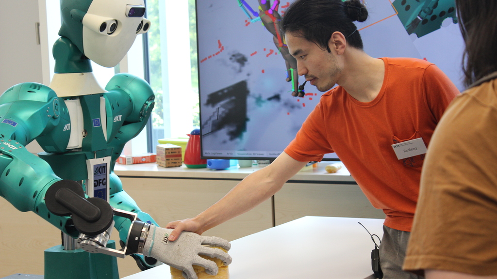 Ein Mitarbeiter arbeitet mit dem humanoiden Roboter ARMAR-6 